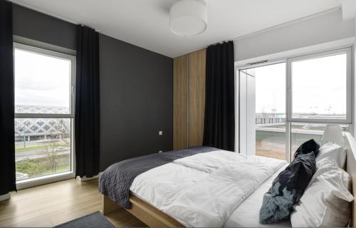 a bedroom with a bed and two large windows at Poznań Apartments Towarowa in Poznań