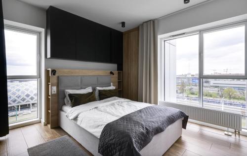 a bedroom with a bed and two large windows at Poznań Apartments Towarowa in Poznań