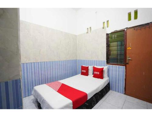 OYO Life 93061 Kost Vicky Syariah في سورابايا: غرفة نوم مع سرير مع وسادتين حمراء