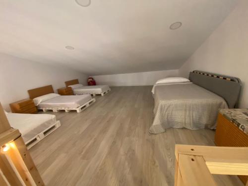 a room with three beds and a wooden floor at Alojamiento en Losa del Obispo 