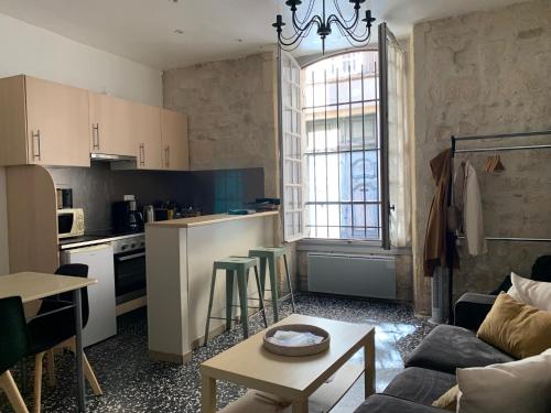 cocina y sala de estar con sofá y mesa en Appartement au coeur du quartier de la Roquette, en Arles