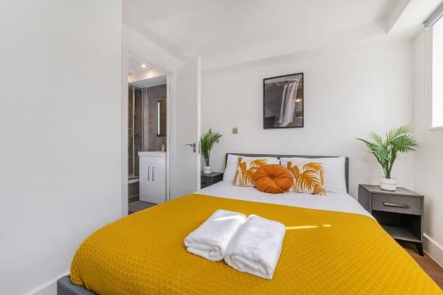 a bedroom with a yellow bed with towels on it at Luxury 2 Bed 2 Bath London Home - Vauxhall, Battersea & Nine Elms in London