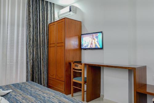 a hotel room with a bed and a desk with a tv at Hotel Divo Palace in Ksamil