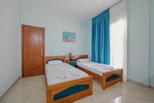 two beds in a room with a window at Hotel Divo Palace in Ksamil