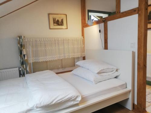 1 cama con sábanas blancas y almohadas en una habitación en Apartament Jesionek agroturystyka, en Jaszkotle