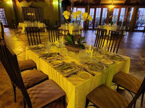 a table with a yellow table cloth and plates and glasses at Villa Paradiso in Hartbeespoort