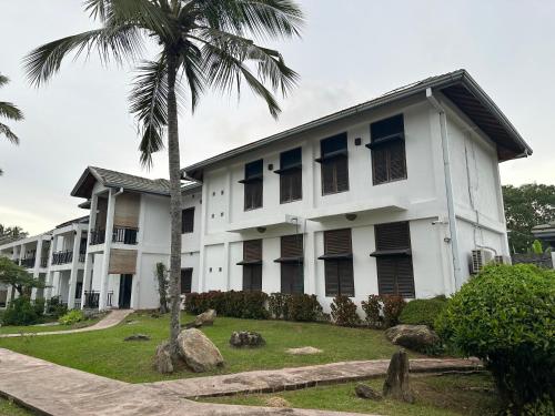 a white building with a palm tree in front of it at Amaluna Resorts in Negombo