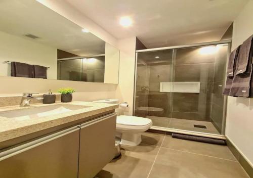 uma casa de banho com um WC e uma cabina de duche em vidro. em NOVO!Apt.condomínio clube,próximo ao Consulado EUA em Porto Alegre