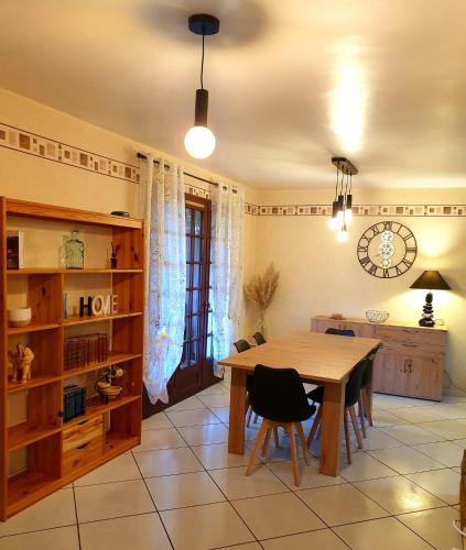 une salle à manger avec une table et une horloge au mur dans l'établissement Jolie maison de vacances, à Gagnac-sur-Cère