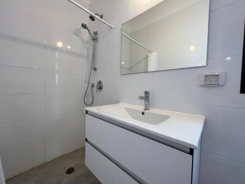 a white bathroom with a sink and a mirror at Menahem Arber 5 Bedrooms in Tel Aviv