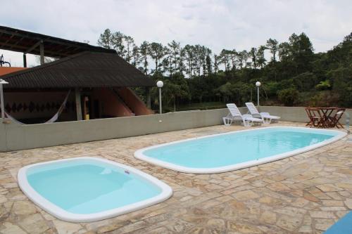a swimming pool on a patio with chairs and a building at Lagamar Ecohotel in Cananéia