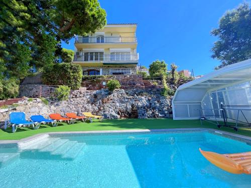 una casa con piscina di fronte a un edificio di Villa con piscina privada climatizada 29ºC a Santa Susanna