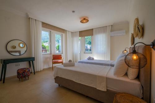 a bedroom with a bed and a desk and windows at Villa Zalin in Ovacik