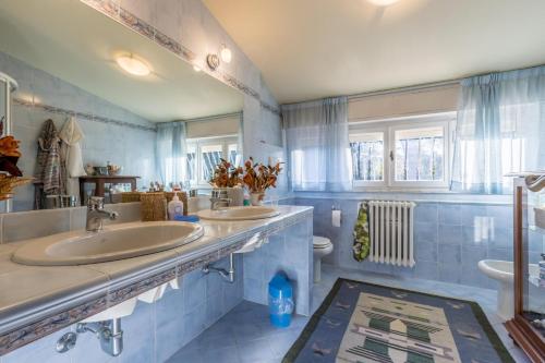 a blue bathroom with two sinks and a toilet at Villa Piero with pool - Happy Rentals in Marina di Pietrasanta