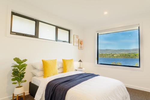 1 dormitorio blanco con 1 cama y 2 ventanas en Hobart 4-bedroom Spacious Waterfront House en Hobart