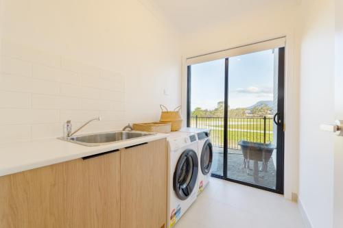 a kitchen with a sink and a washing machine at Hobart Luxury Waterfront Retreat 4BR Award-Winning Stay in Hobart