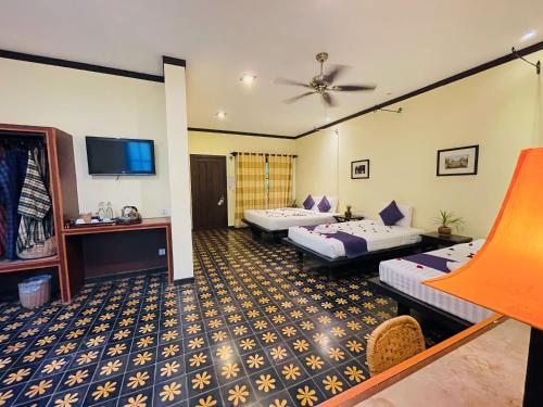 a hotel room with two beds and a flat screen tv at Residence Indochine D'angkor in Siem Reap
