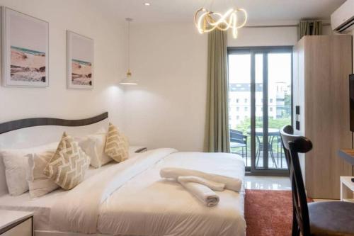 a bedroom with a large white bed and a balcony at The Lennox Studio @Airport Residential in Accra