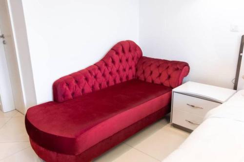 a red couch sitting in a room next to a bed at The Lennox Studio @Airport Residential in Accra