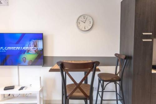 two chairs and a table and a clock on a wall at The Lennox Studio @Airport Residential in Accra