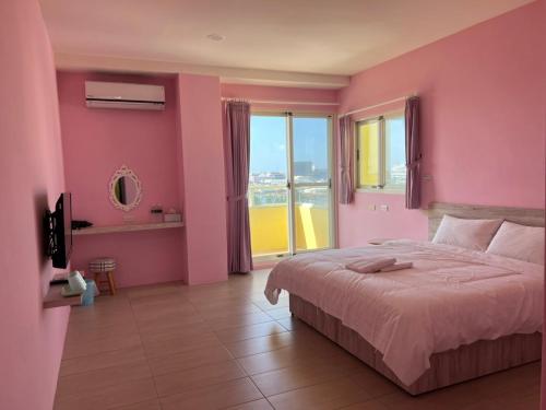 Habitación de color rosa con cama y ventana grande. en 情人灣二館, en Magong