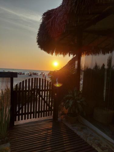 a sunset over a beach with a fence and the ocean at Espaço Fateixa in Jericoacoara