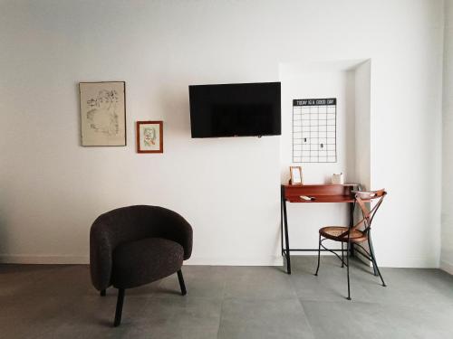 Zimmer mit einem Stuhl, einem Schreibtisch und einem TV in der Unterkunft La tua casa a Piazza del Popolo in Rom