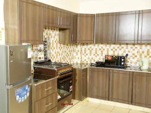 a kitchen with wooden cabinets and a stainless steel refrigerator at Upperhill suites in Kisii
