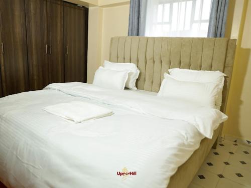 a large white bed with white sheets and pillows at Upperhill suites in Kisii