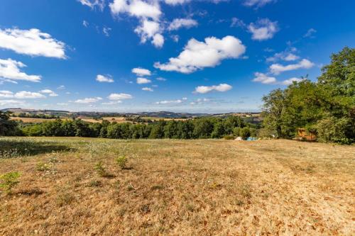 a field with trees and a blue sky with clouds at Les Juliannes - Gîte La Pierre Etoilée Piscine Jardin in Paulinet