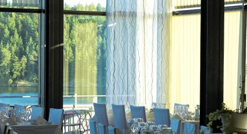 a room with tables and chairs in front of a window at Skåvsjöholm, hotell & konferens in Åkersberga