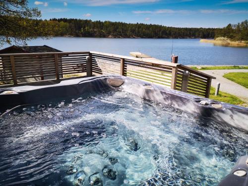 a hot tub with water in it next to a lake at Skåvsjöholm, hotell & konferens in Åkersberga
