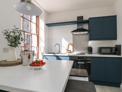 a kitchen with blue cabinets and a bowl of fruit on a counter at Llety Pen Deitsh 1 in Caernarfon