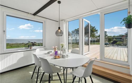 a dining room with a white table and chairs and large windows at Beautiful Home In Allinge With 3 Bedrooms in Allinge