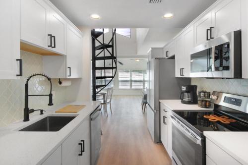 a kitchen with white cabinets and a spiral staircase at Watch the Sunrise on Lake Louisa in Clermont