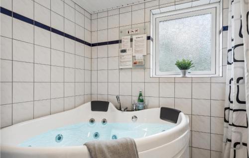 a bath tub in a tiled bathroom with a window at 4 Bedroom Cozy Home In Brovst in Brovst