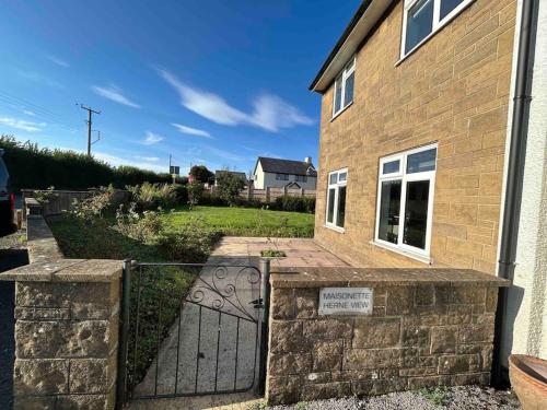ein Tor zu einem Backsteinhaus mit einem Schild darauf in der Unterkunft Herne view maisonette beautiful countryside views in Ilminster