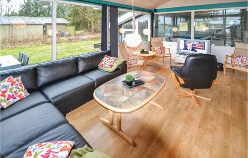 a living room with a black leather couch and a table at Awesome Home In Løkken With Sauna in Lønstrup