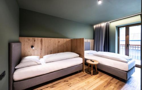 two beds in a room with a green wall at Hotel Alpenroyal in Castelrotto