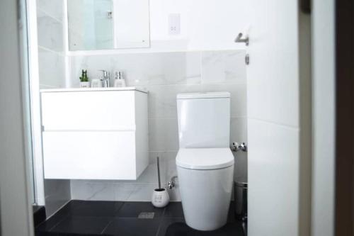 a bathroom with a white toilet and a sink at The Luxe - @ Embassy Gardens Cantonments in Cantonments