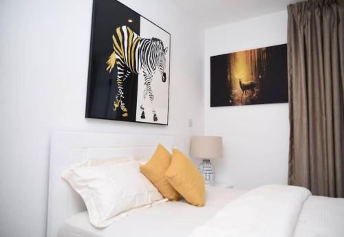 a white bedroom with a zebra picture on the wall at The Luxe - @ Embassy Gardens Cantonments in Cantonments