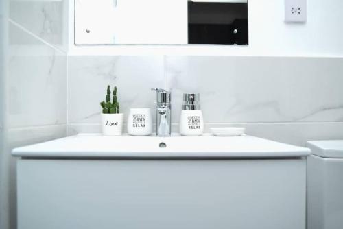 a white bathroom sink with two cups on it at The Luxe - @ Embassy Gardens Cantonments in Cantonments