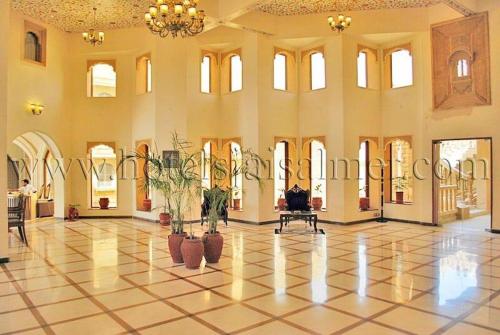 a large building with a lobby with plants on the floor at Hotel Deoki Niwas Palace in Jaisalmer