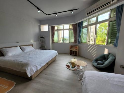 1 dormitorio con 2 camas, silla y ventanas en 敘時光行旅 Telling Story House, en Sanxing