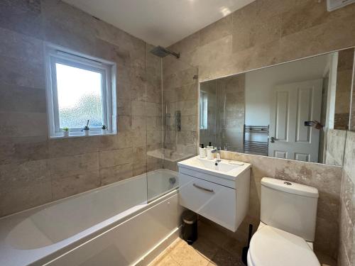 a bathroom with a toilet and a tub and a sink at Super 1 bedroom in a stunning apartment with shared kitchen and living room - 2C The Charteris in London