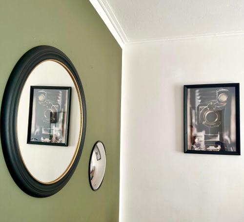 een ronde spiegel op een groene muur met twee foto's bij Chez Ethan, 5 min à pied de l'Acropole in Athene