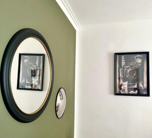 a round mirror on a green wall with two pictures at Chez Ethan, 5 min à pied de l'Acropole in Athens