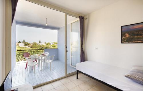 ein Schlafzimmer mit einem Bett und einen Balkon mit einem Tisch und Stühlen in der Unterkunft Amazing Apartment In Isca Marina With Wifi And 1 Bedrooms in Badolato