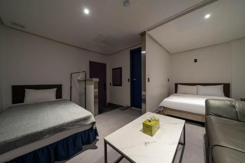a hotel room with two beds and a couch at Pacific7 Hotel in Pyeongtaek
