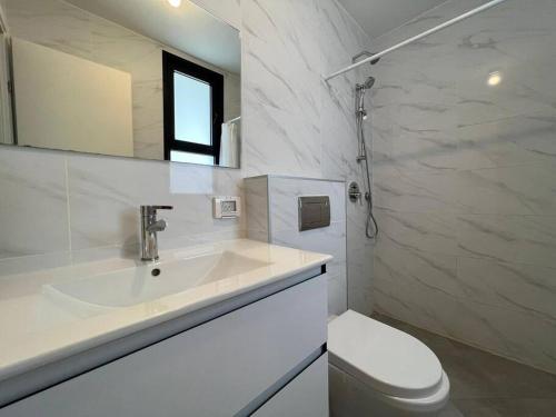 a white bathroom with a sink and a toilet at Menahem Arber 4 Bedroom in Tel Aviv